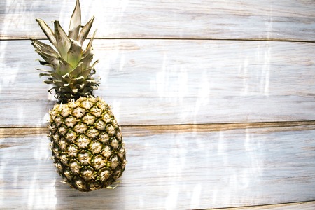 A whole ripe pineapple on an old wooden background.の写真素材