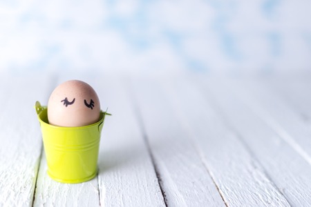 Easter eggs in a small bucket on a white blurred backgroundの写真素材