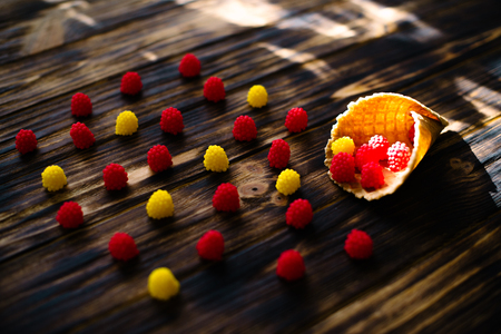 Waffle cone with berries on a wooden background.
