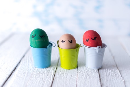 Easter eggs in a small bucket on a white blurred backgroundの写真素材