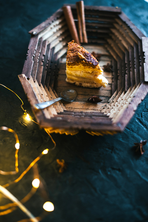 Cake on a wooden tray on a black matte background.