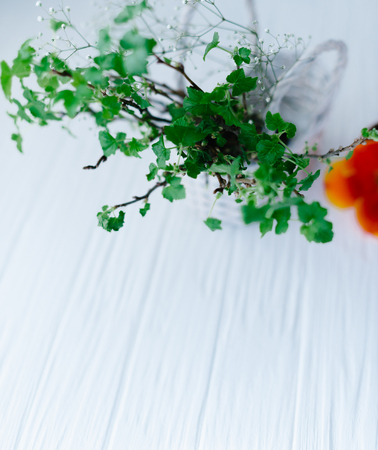 Branches with green leaves in a basket on a wooden background.の写真素材