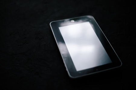 Tablet on a black matte cement background.の写真素材