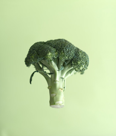 Broccoli in the air on a green background.