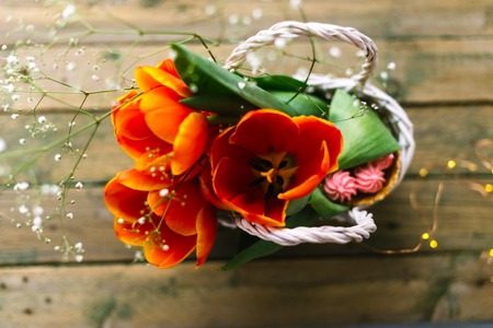 Tulips in a white basket on a wooden background with garlands in the background.の写真素材