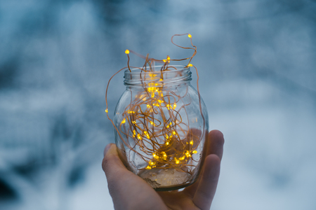 Glass jar with garlands in hand in winter.の写真素材