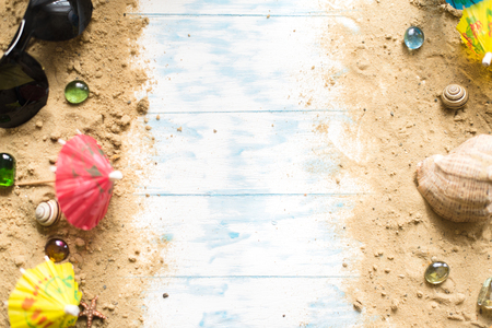 Beach still life. Black glasses with cocktail umbrellas, seashell on sand on a wooden background.の写真素材