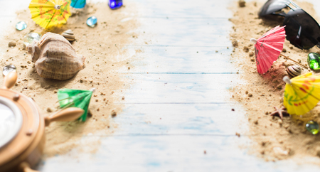 Beach still life. Black glasses with cocktail umbrellas, seashell on sand on a wooden background.の写真素材