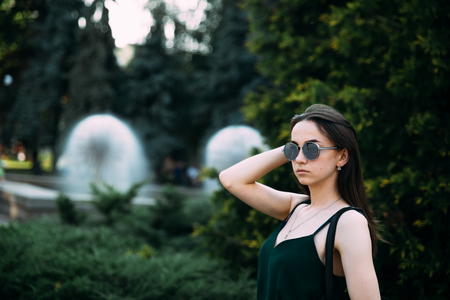 Beautiful young girl in a park in sunglasses.の写真素材