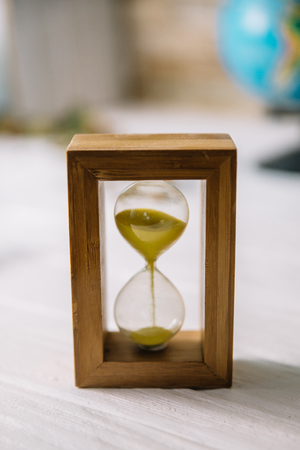 Hourglass on white wooden table with blurred background