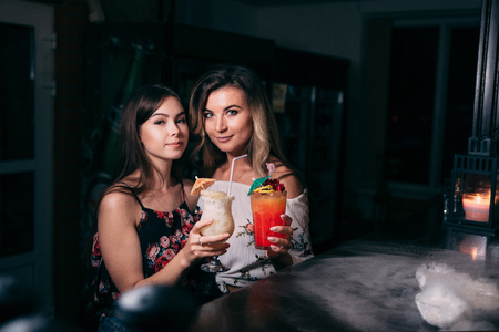 Young beautiful girls with cocktails near the bar.の写真素材