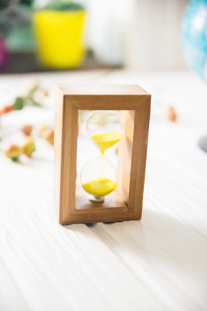 Hourglass on white wooden table with blurred background