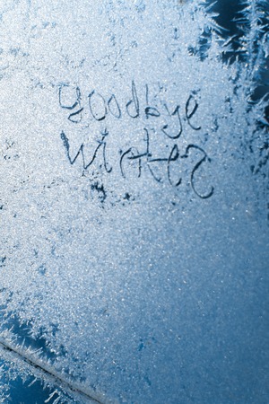 The inscription: goodbye, winter. On a frozen winter window in frosty patterns.の写真素材