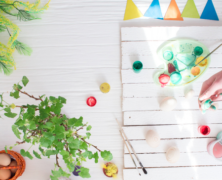 Man painting Easter eggs still life on a white wooden background.の写真素材