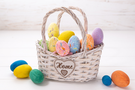 Easter eggs in a white basket on a white wooden background.の写真素材