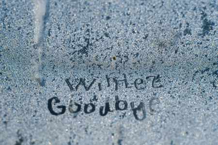 The inscription: goodbye, winter. On a frozen winter window in frosty patterns.の写真素材