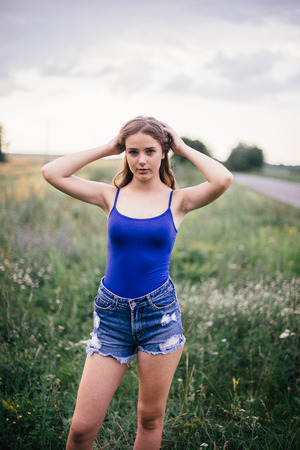 Beautiful girl in short shorts and in a blue T-shirt on the field.の写真素材