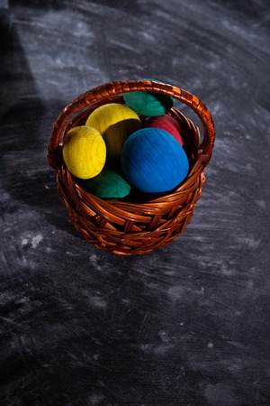 Easter multicolored eggs in a basket on a dark blurred background.の写真素材