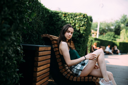 A girl in a black T-shirt and shorts in a park on a benchの写真素材