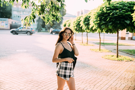 Brunette girl in a summer day in the city wearing round sunglasses.の写真素材