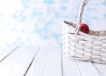 Easter eggs in a white basket on a wooden background.の写真素材
