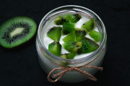 Yogurt with kiwi slices on a black background.の写真素材