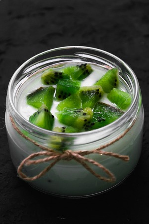 Yogurt with kiwi slices on a black background.の写真素材