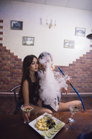 Two girls at a table with snacks and hookah at a nightclub.の写真素材