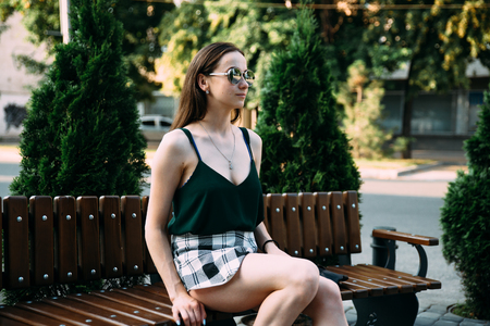 A girl in a black T-shirt and shorts in a park on a benchの写真素材