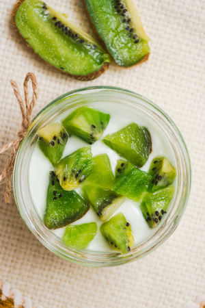 Yogurt with kiwi slices on a wooden white backgroundの写真素材