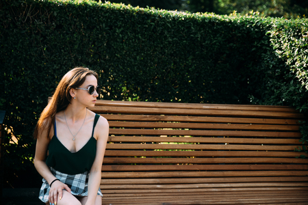 A girl in a black T-shirt and shorts in a park on a benchの写真素材