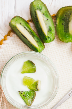 Yogurt with kiwi slices on a wooden white backgroundの写真素材