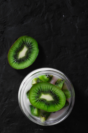 Yogurt with kiwi slices on a black background.の写真素材