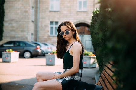 A girl in a black T-shirt and shorts in a park on a benchの写真素材