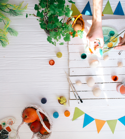 Man painting Easter eggs still life on a white wooden background.の写真素材