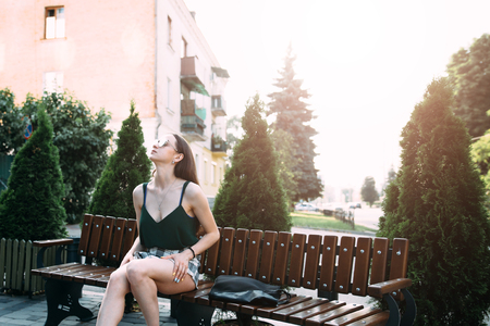 A girl in a black T-shirt and shorts in a park on a benchの写真素材
