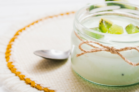 Yogurt with kiwi slices on a wooden white backgroundの写真素材