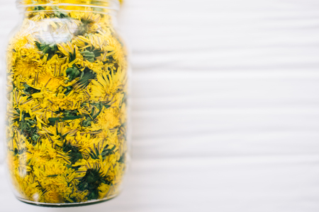 Dandelions in a glass jar on a white background.の写真素材