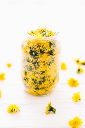 Dandelions in a glass jar on a white background.の写真素材