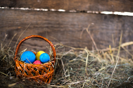 Easter eggs in a basket on a hay with a blurred background.の写真素材
