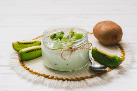 Yogurt with kiwi slices on a wooden white backgroundの写真素材