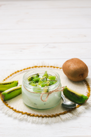 Yogurt with kiwi slices on a wooden white backgroundの写真素材