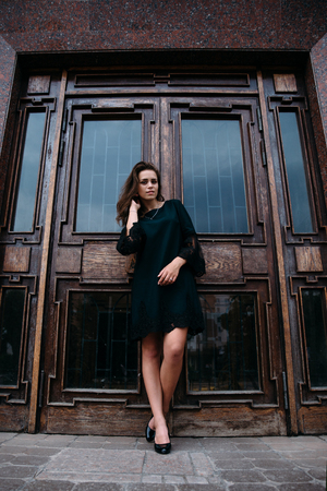 Young girl in green dress near old big building door.の写真素材