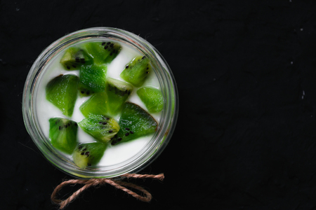 Yogurt with kiwi slices on a black background.の写真素材