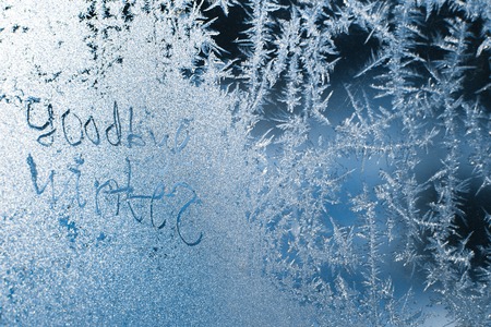 The inscription: goodbye, winter. On a frozen winter window in frosty patterns.