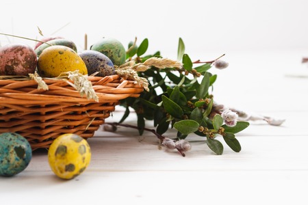Easter eggs in a basket on a white wooden background.の写真素材