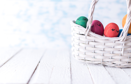 Easter eggs in a white basket on a wooden background.の写真素材