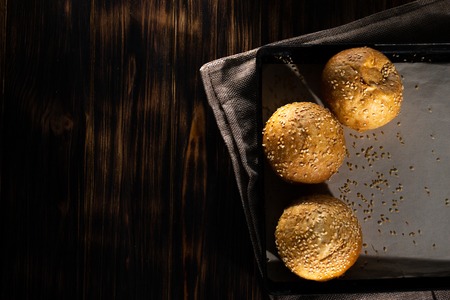 Homemade buns on burlap on wooden background.