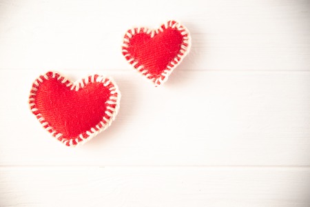 Red knitted soft fabric hearts on white background.の写真素材
