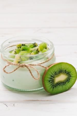 Yogurt with kiwi slices on a wooden white backgroundの写真素材
